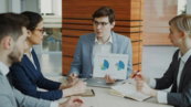 man-presenting-charts-to-colleagues-in-a-meeting-.jpg Man presenting charts to colleagues in a meeting.